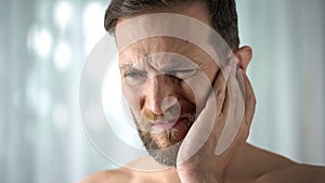 Ill man feeling ear pain, health care, neurological infection, itchiness otitis photo