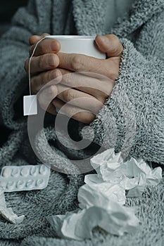 ill man warming himself with a cup of herbal tea