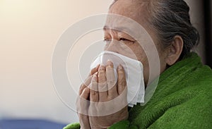 Ill mature woman covered with blanket blowing running nose sneeze in tissue suffer from allergy flu