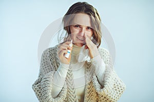 Ill modern middle age woman with napkin using nasal spray photo