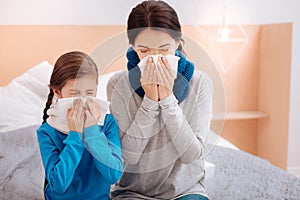 Ill mother and daughter sneezing together