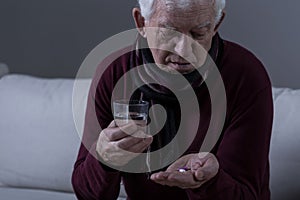 Ill senior man taking medicament