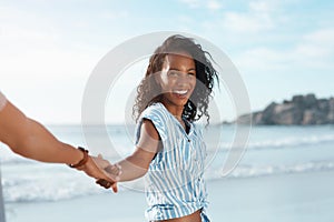 Ill show you where the funs at. POV shot of a young woman holding her boyfriends hand at the beach.