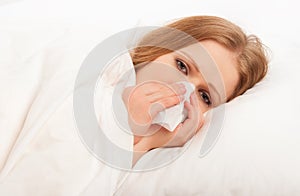 Ill sick girl sneezes into a handkerchief in bed