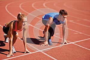 Ill take you on. Shot of two young people getting ready to race on an athletics track.
