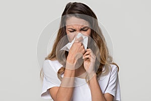 Ill woman blowing running nose in tissue isolated on background