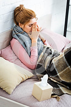 Ill woman with grey scarf lying in bed