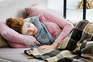 Ill woman with grey scarf sleeping on bed