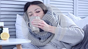 Ill woman lying on bed with flu at grey bedroom