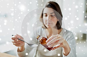 Ill woman pouring medication from bottle to spoon