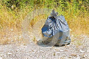Illegal dumping - garbage plastic bag left in the nature