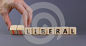 Illiberal or liberal symbol. Businessman turns wooden cubes and changes the word illiberal to liberal. Beautiful grey background.