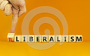 Illiberalism or liberalism symbol. Businessman turns a cube and changes the word `illiberalism` to `liberalism`. Beautiful ora