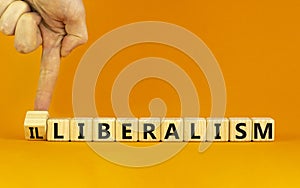 Illiberalism or liberalism symbol. Businessman turns a cube and changes the word `illiberalism` to `liberalism`. Beautiful ora