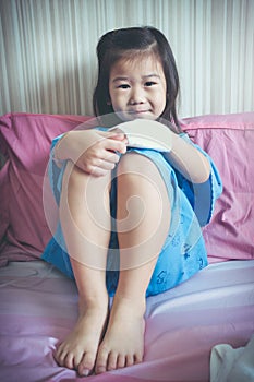 Illness asian child admitted in hospital with band-aid on hand.