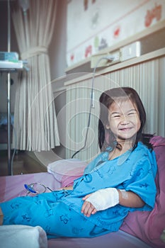 Illness asian child admitted in hospital with IV drip on hand.