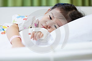 Illness child in hospital, saline intravenous (IV) on hand asian