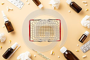 Illness concept. Top view photo of empty shopping cart medicines transparent brown bottles pills blisters thermometer and crumpled