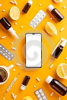 Illness concept. Top view vertical photo of remedy spray and syrup bottles smartphone pills blisters thermometer cut lemon and cup