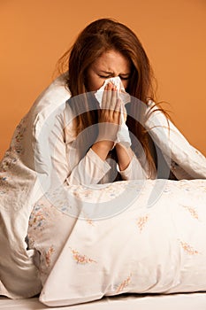 illness flu - Young Woman Lying On Bed Infected With Allergy Blowing Her Nose