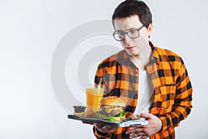 Illness sad young man in shirt put hand on pain abdomen, stomach-ache, standing and holding burger isolated on white background. P