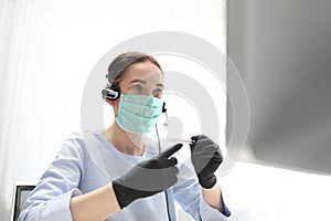 Illness at work, elevated temperature. A woman in a surgical mask works on the computer. Work during the plague