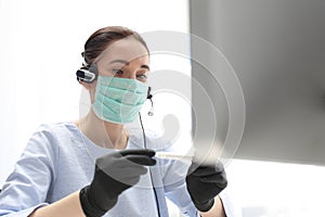 Illness at work, elevated temperature. A woman in a surgical mask works on the computer. Work during the plague