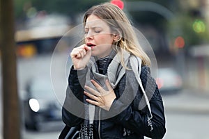 Illness young woman coughing in the street