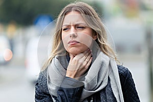 Illness young woman with terrible throat pain walking to the street.