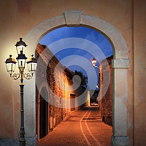 Illuminated alleyway with arched gate and lantern