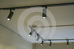 Illuminated black track light on ceiling. Modern LED Hanging rotating spot light.