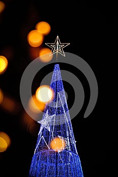 Illuminated blue Christmas tree with a star-shaped light on a dark night