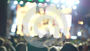 Illuminated and blurry dancing crowd at a concert. Silhouette of people at a party during the concert. People wave their hands,