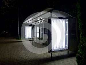 Illuminated bus shelter at night in residential neighborhood