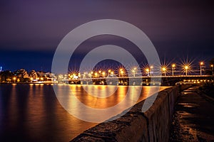 Illuminated Chernavsky bridge at night, view to right bank or downtown of Voronezh city, dramatic cityscape with reflection