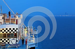 Illuminated cruise ship with people on deck