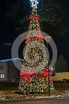 Illuminated and decorated Christmas tree, covered with snow