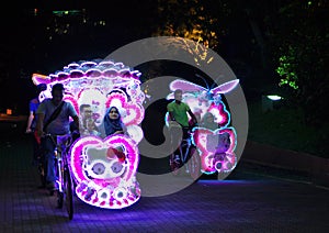 Illuminated decorated trishaw with soft toys at night in Malacca, Malaysia