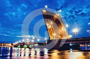 An illuminated drawbridge in Saint Petersburg at white night and reflections on water