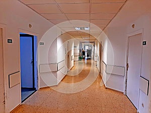 Illuminated and empty hospital corridor with many rooms