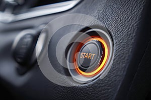 Illuminated engine start button in modern vehicle dashboard surrounded by textured black leather interior promoting easy push-to-
