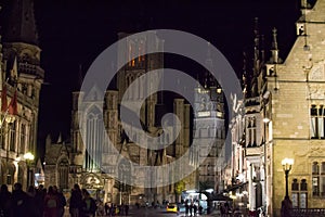 Illuminated facade of Saint Nicholas` Church Sint-Niklaaskerk with the clock tower of Belfry of Ghent Het Belfort at the