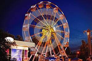 Illuminated ferris wheel in amusement park at a night city