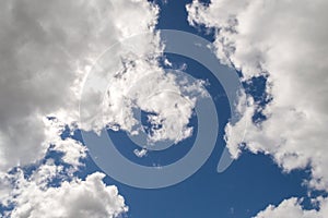 Illuminated fluffy white clouds brightly back lit, blue sky.