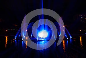 The illuminated fountain at night with the blue soft beams