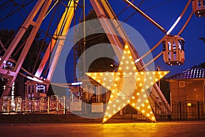 Illuminated glowing star in amusement park at the night city