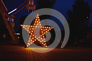 Illuminated glowing star in amusement park at the night city