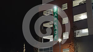 Illuminated Green Parkade Sign on Building Exterior at Night