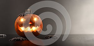 Illuminated halloween pumpkin with spiders dark background front