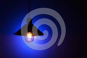 Illuminated hanging led light bulb over blue background
